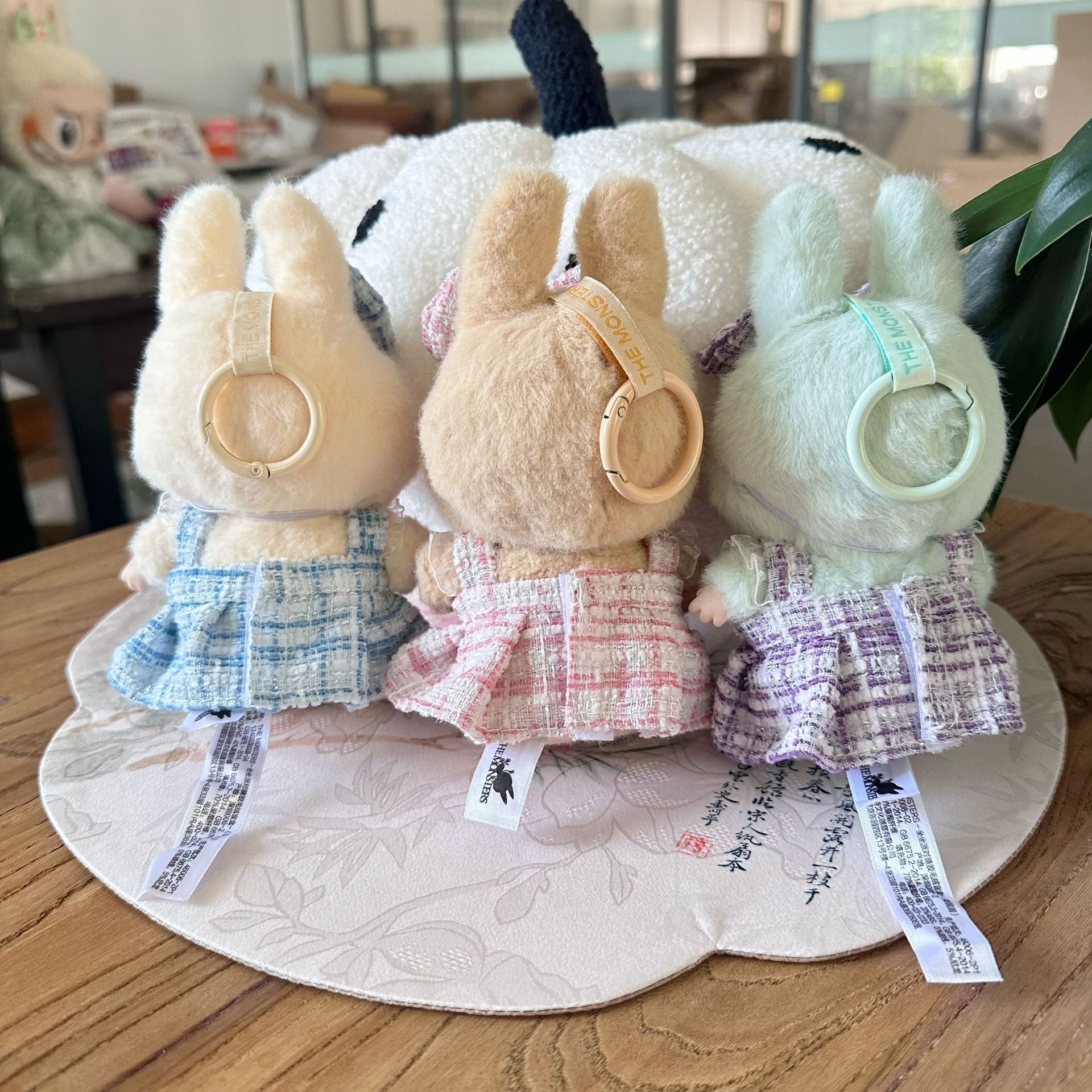Three plush toys with different outfits on a round mat.