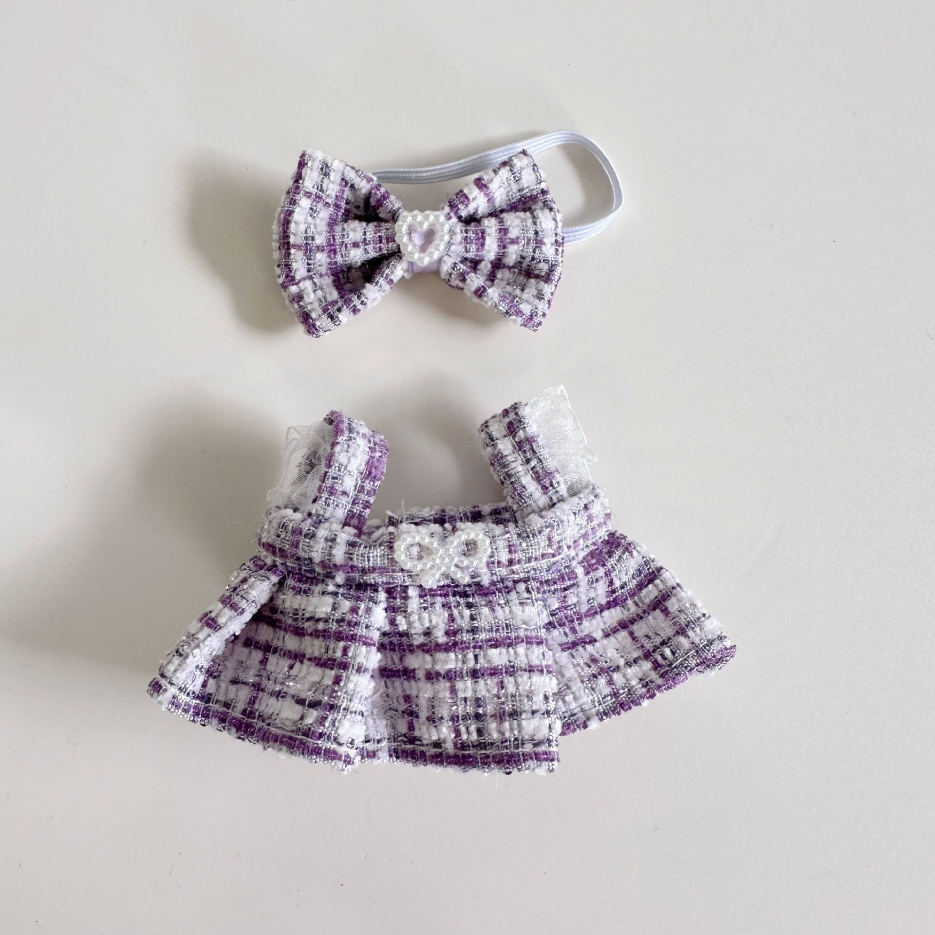 Purple and white checkered baby outfit with matching headband on a light gray background