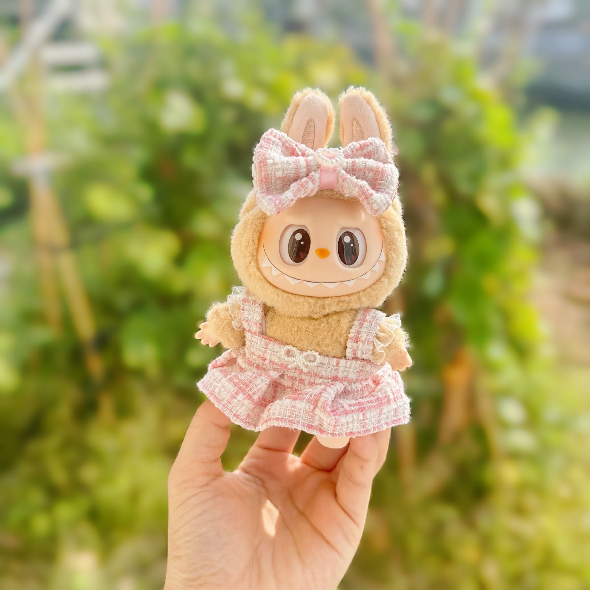 Plush toy with a bow held by a hand against a blurred green background