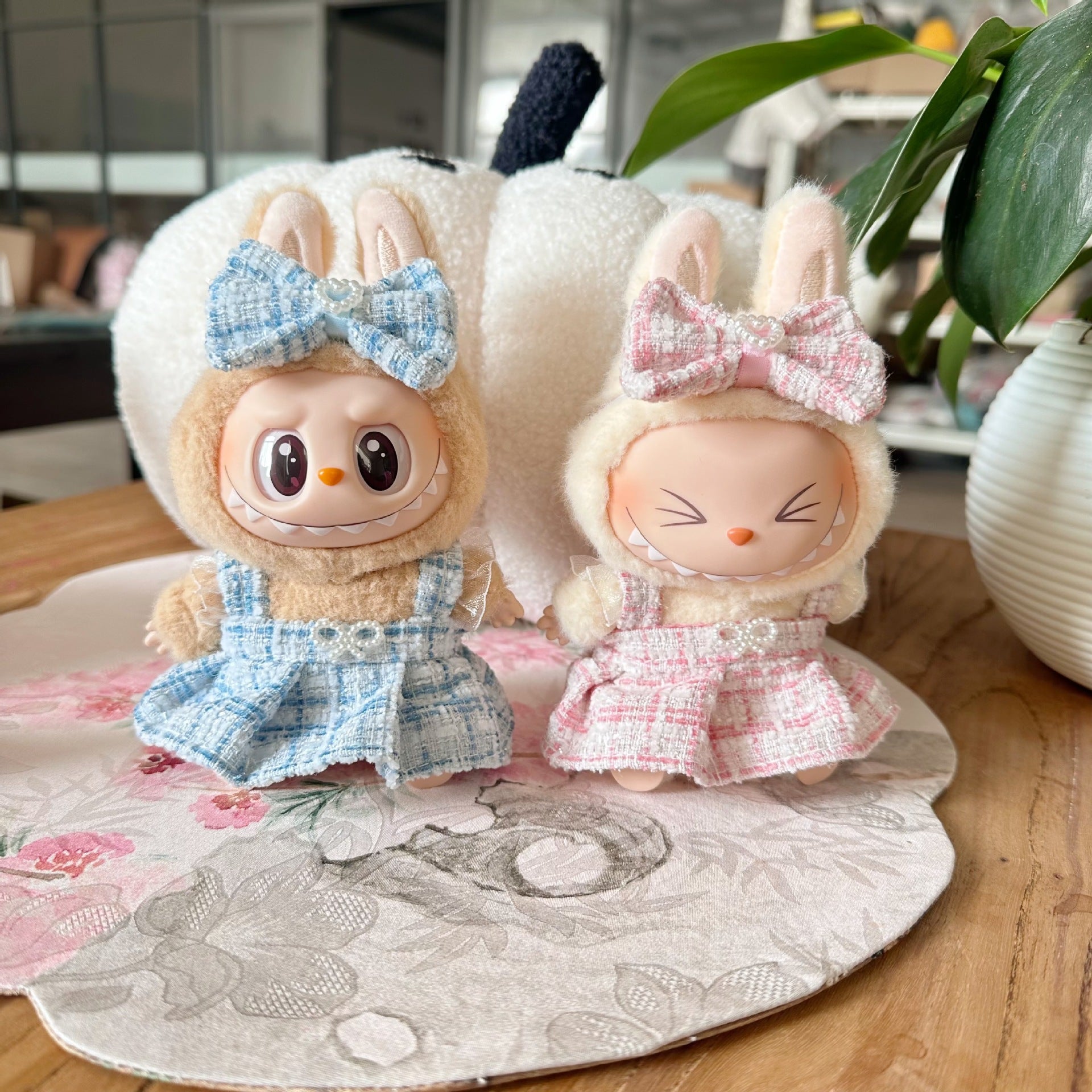 Two plush toys with bunny ears and bows on a decorative plate.