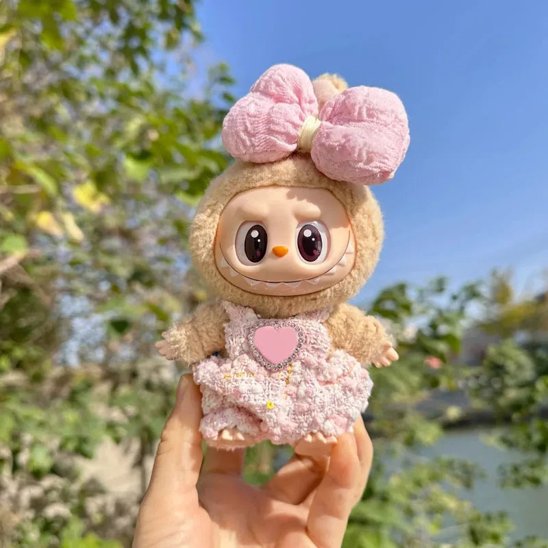 Toy figure with a pink bow and heart on a blurred natural background