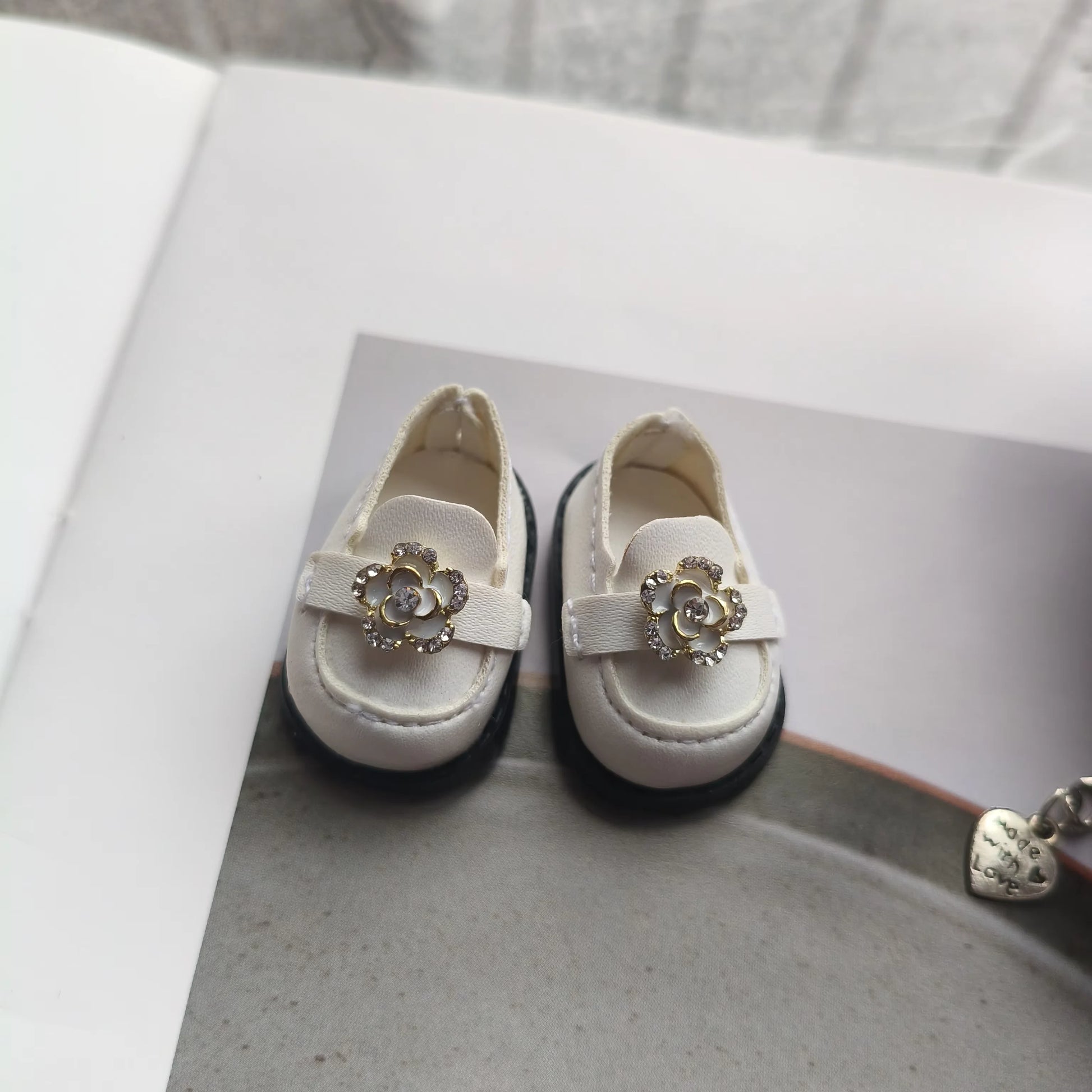 White children's shoes with decorative bows on a gray surface