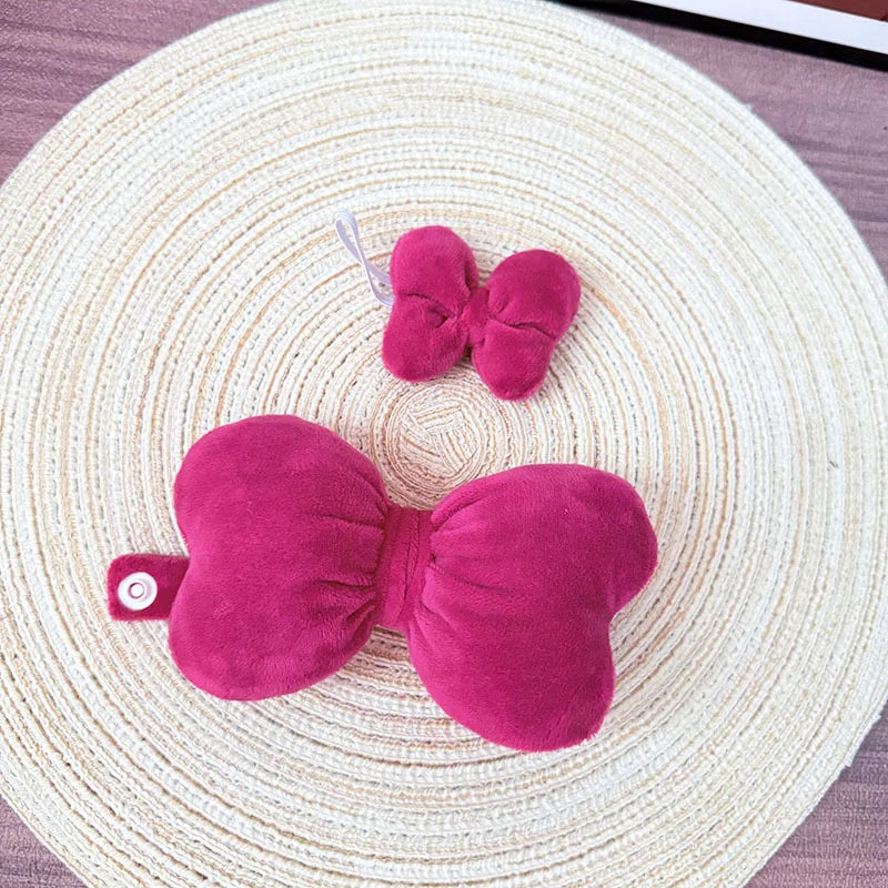 Pink butterfly-shaped plush toy on a woven mat