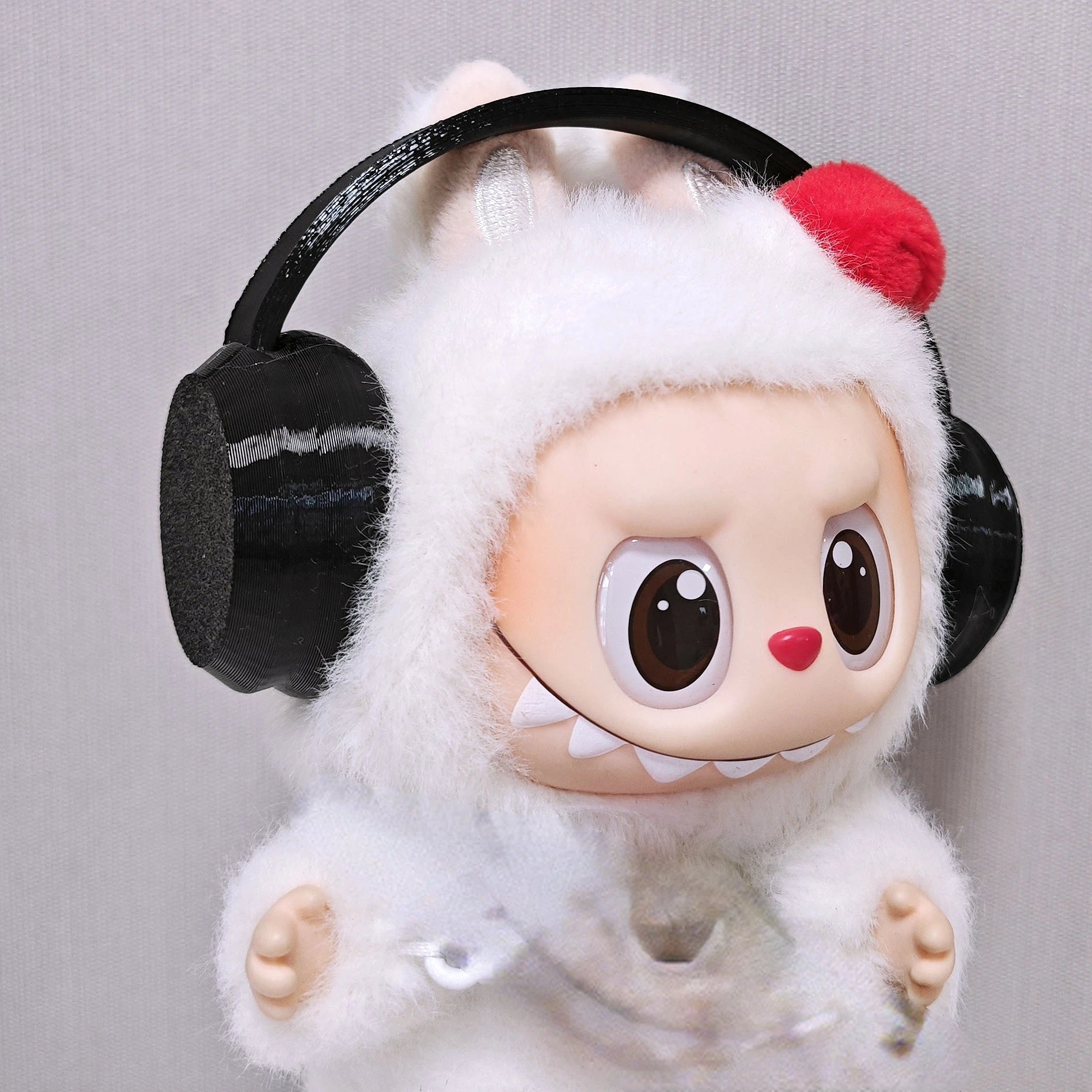 Toy figure with large eyes, a red nose, and black headphones on a gray background