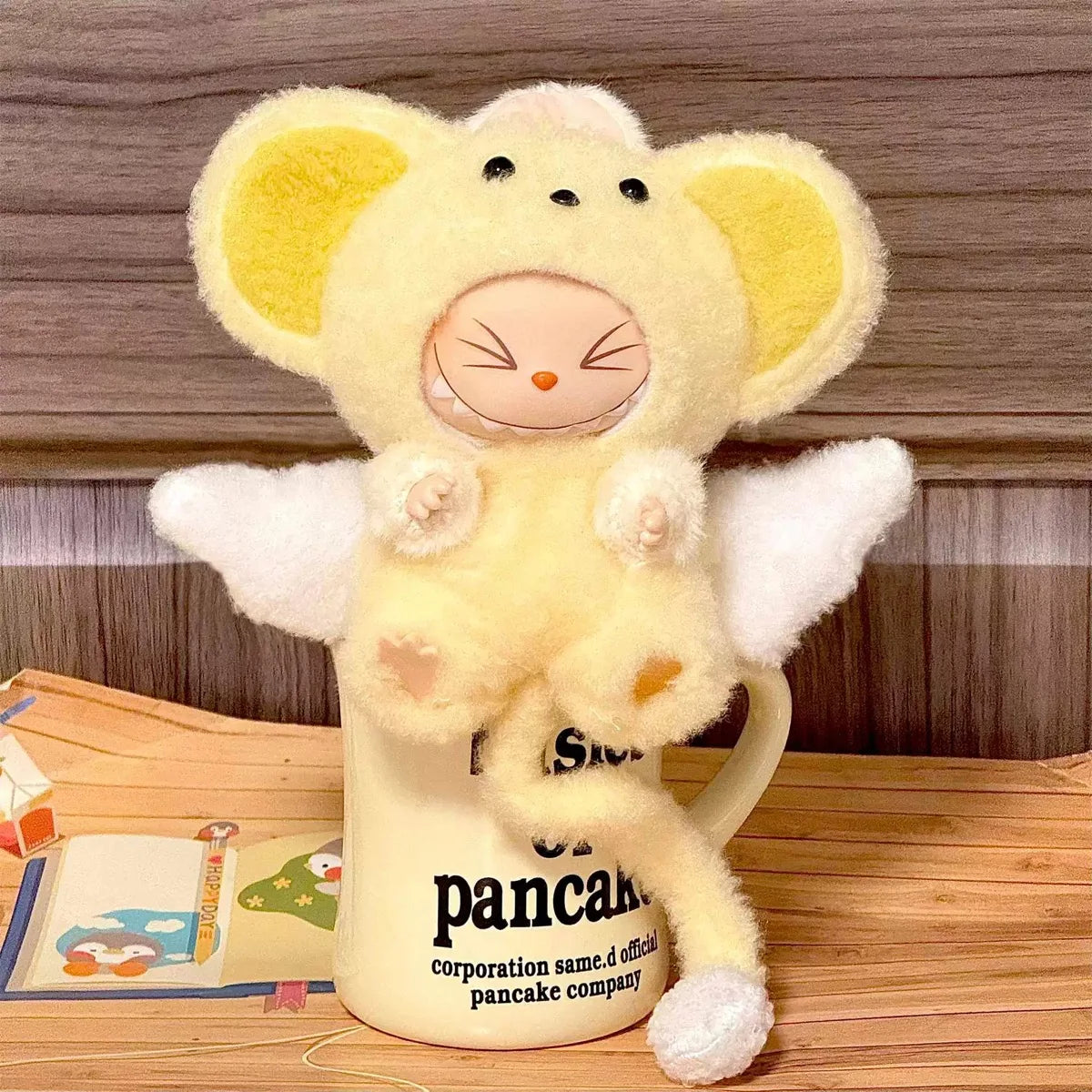 Plush toy resembling a cartoon character on a mug with text, against a wooden background.