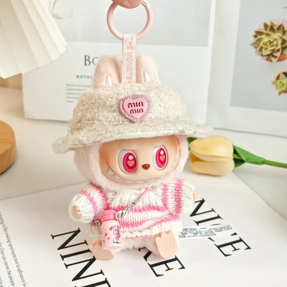 Cute plush toy keychain with a hat and pink outfit on a white surface.