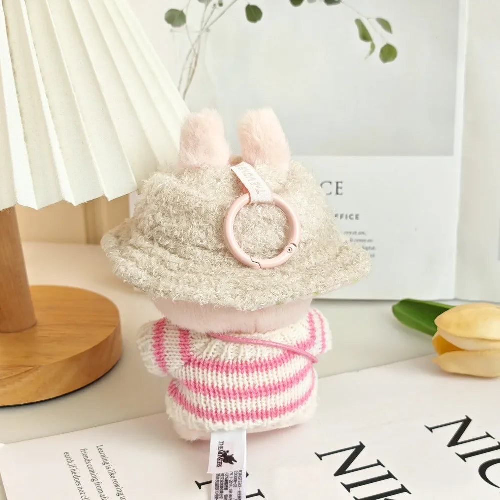 Small plush toy with a pink and white striped body and fluffy beige hat on a surface.