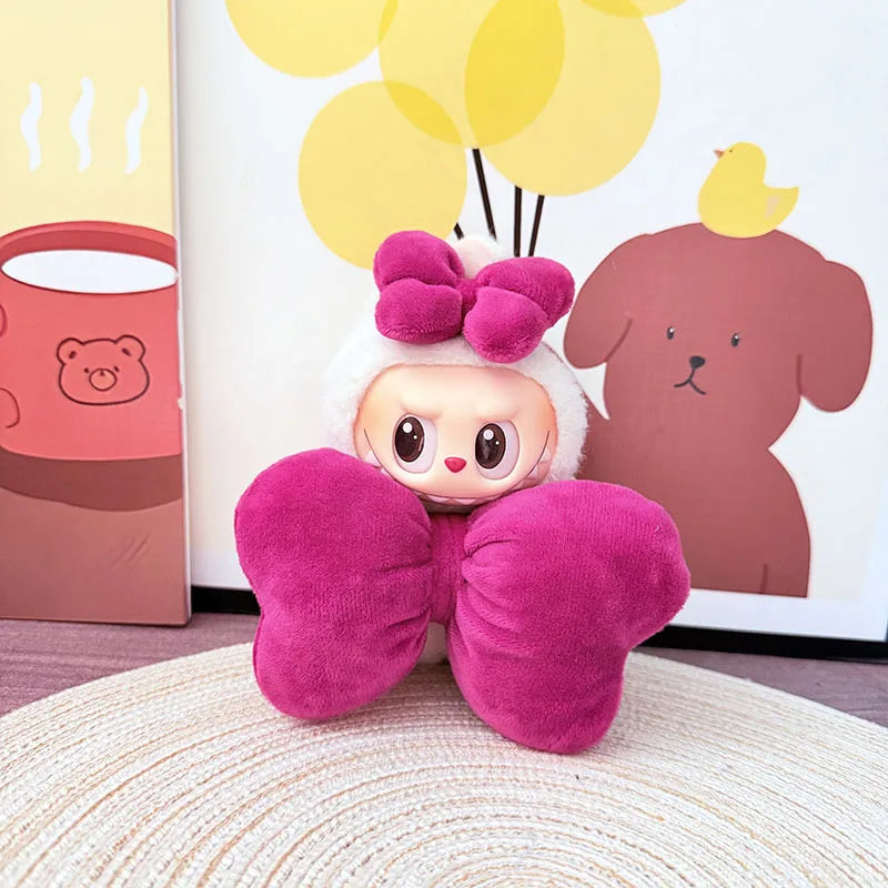 Plush toy with pink bow and white head in front of a framed picture with cartoon characters.