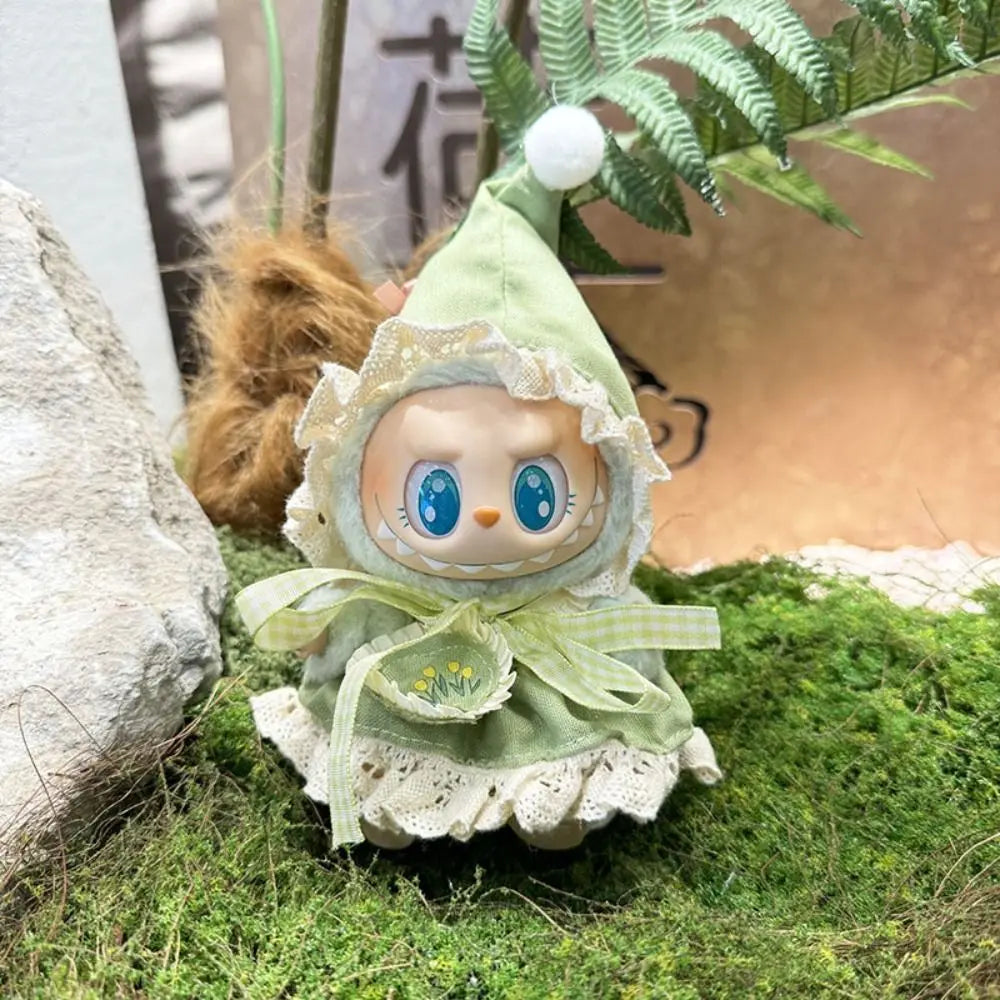 Small doll with a green hood and dress on a grassy surface