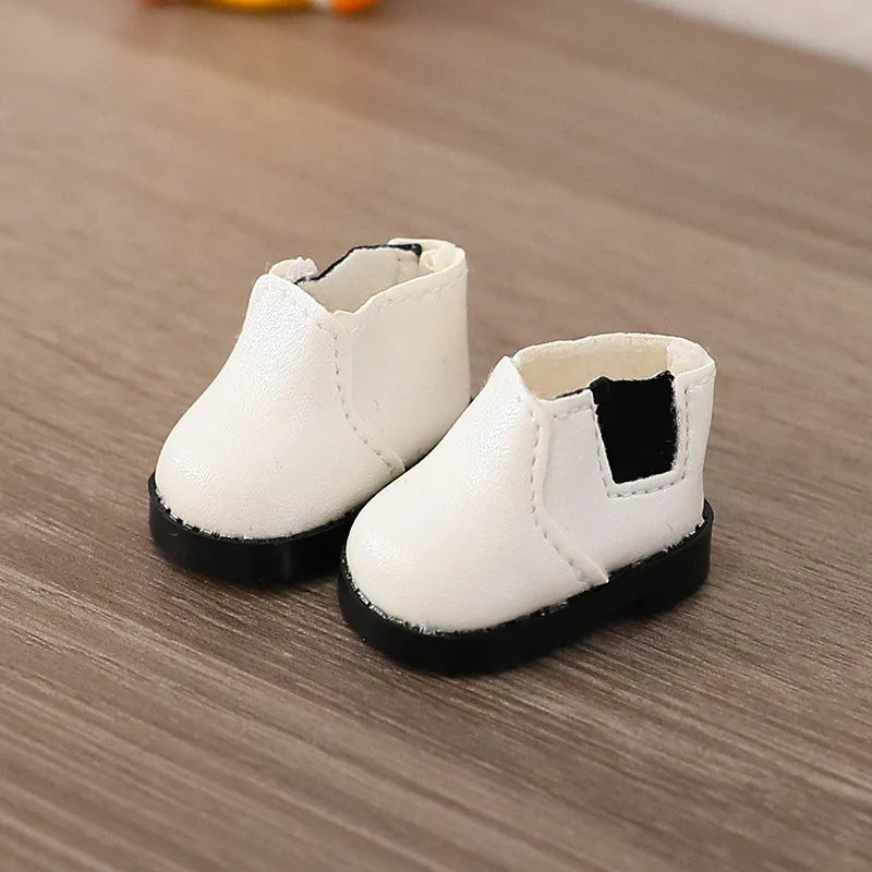 Pair of white children's boots with black soles on a wooden surface