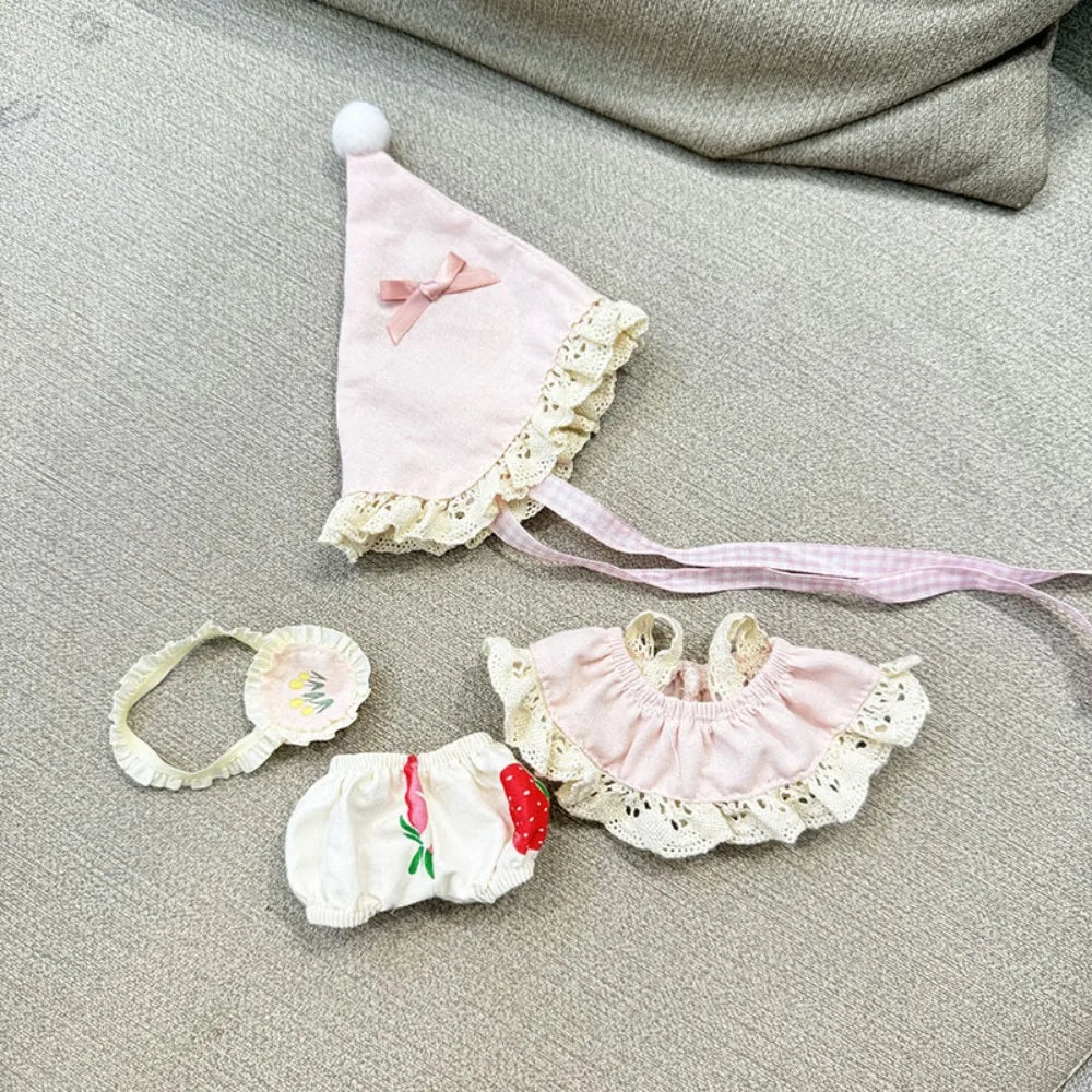 Set of baby accessories including a bonnet, headband, and bloomers on a textured surface.