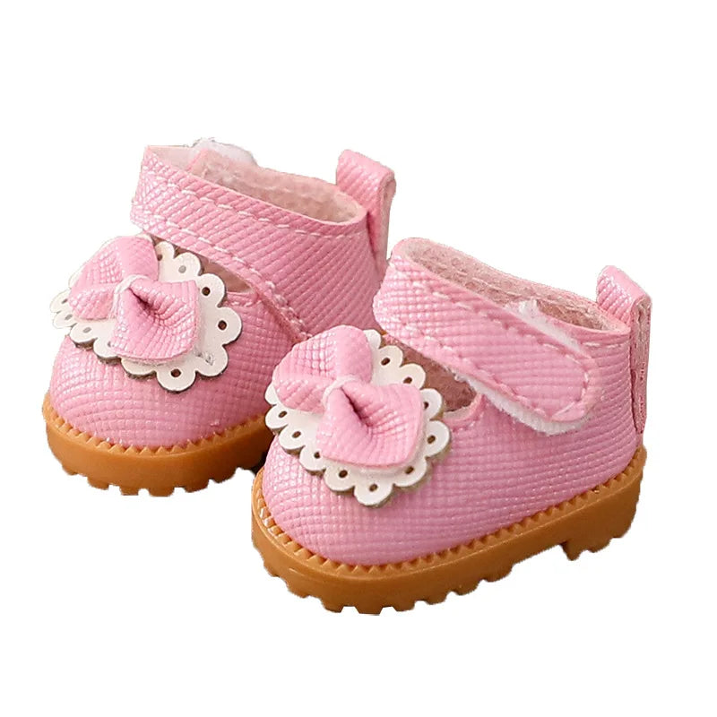 Pink baby shoes with white floral details on a white background
