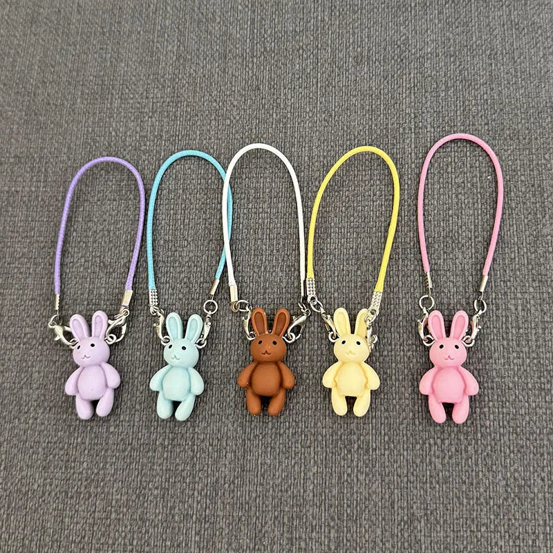 Five colorful bunny keychains on a gray background