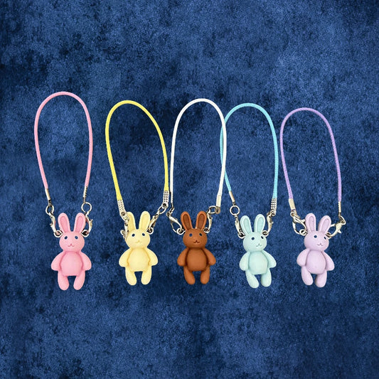 Five colorful bunny keychains on a textured blue background