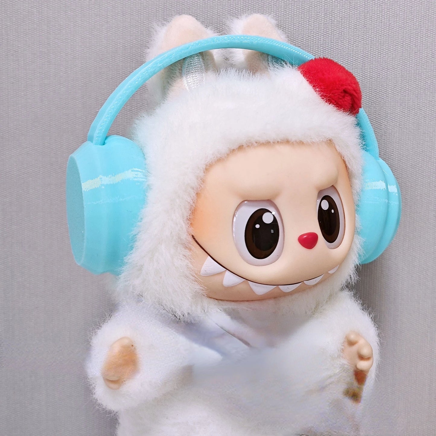 Toy figure with blue headphones and a white outfit on a gray background