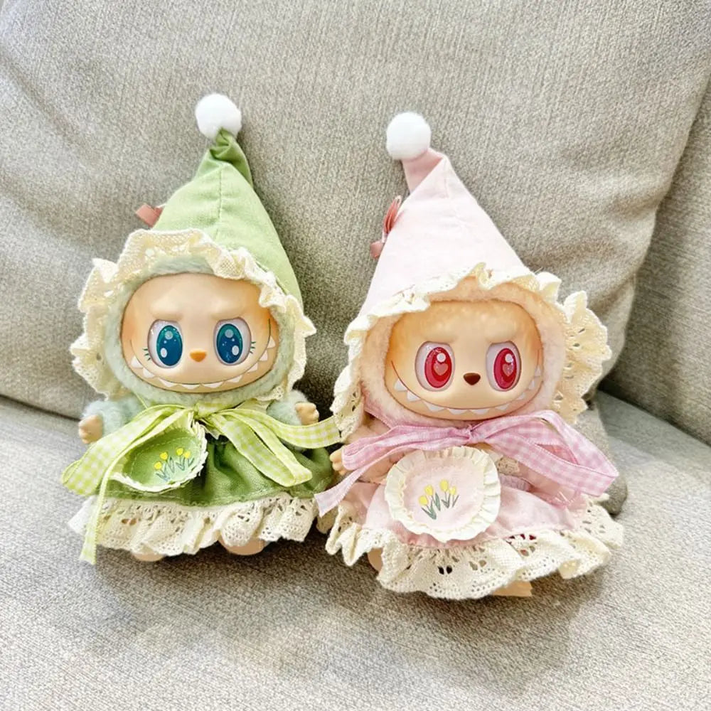 Two small plush toys with colorful hats and dresses on a neutral background