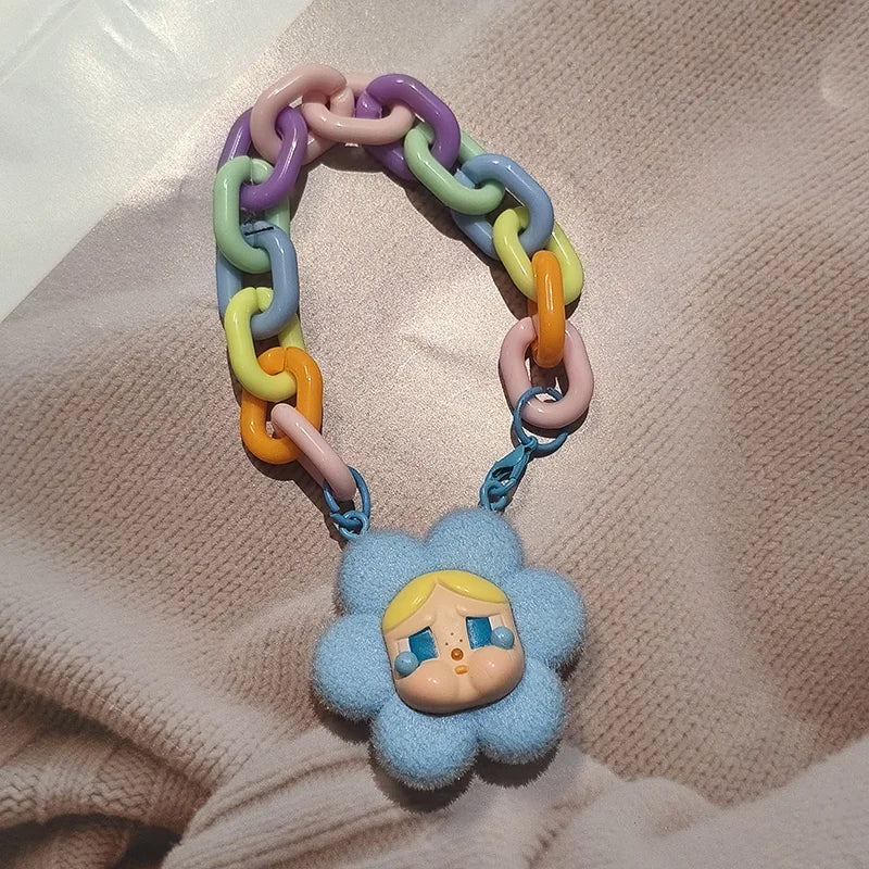 Colorful chain teething toy with a blue flower-shaped character on a beige fabric background