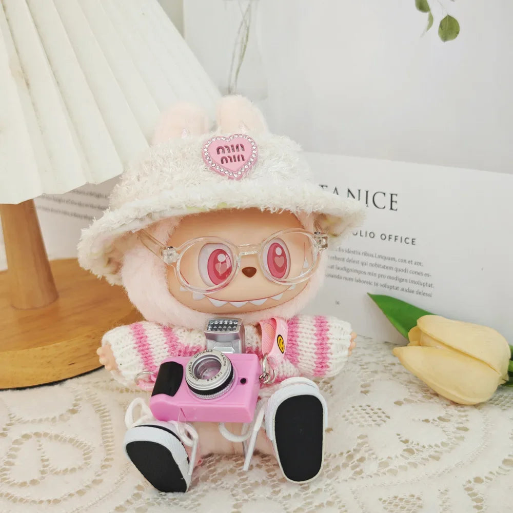 Stuffed toy with pink camera, white hat, and glasses on a light surface.