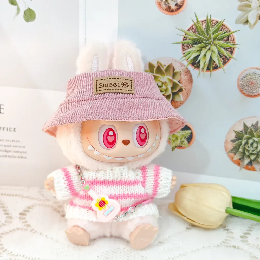 Toy character wearing a pink hat and striped sweater with succulents in the background