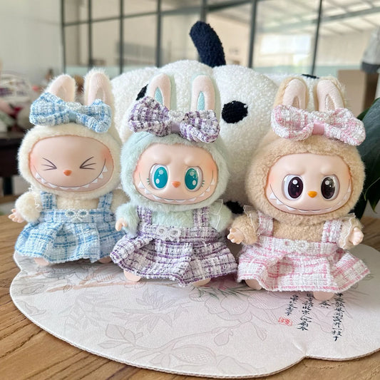 Three plush toys with bunny ears and colorful bows on a wooden surface.