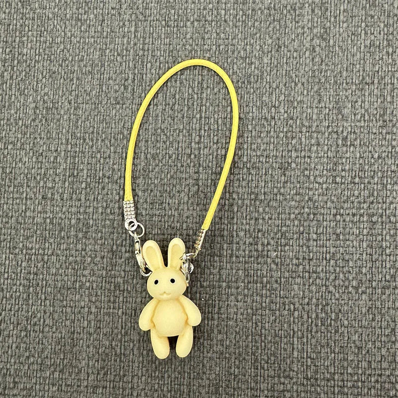 Yellow plush bunny keychain on a gray textured background