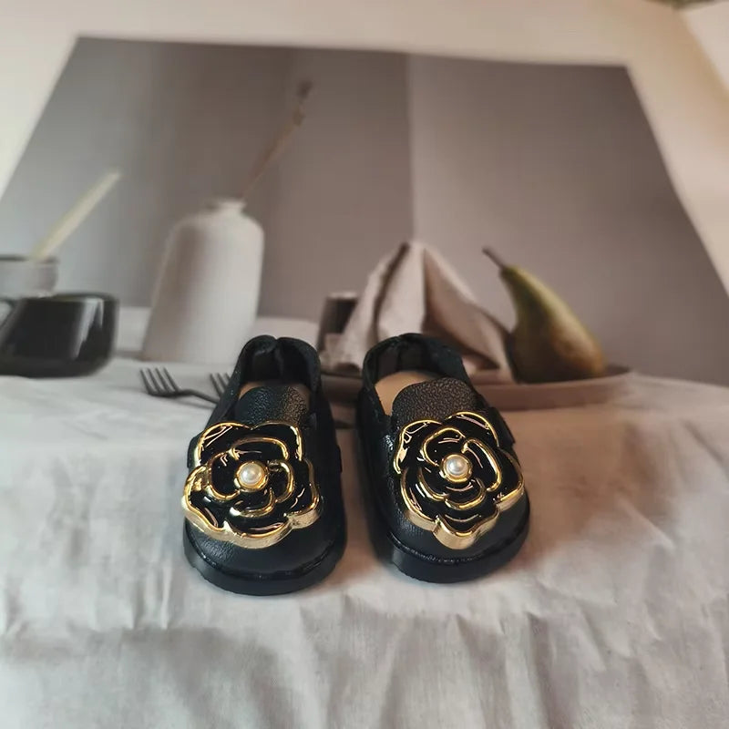 Black shoes with gold floral designs on a white surface