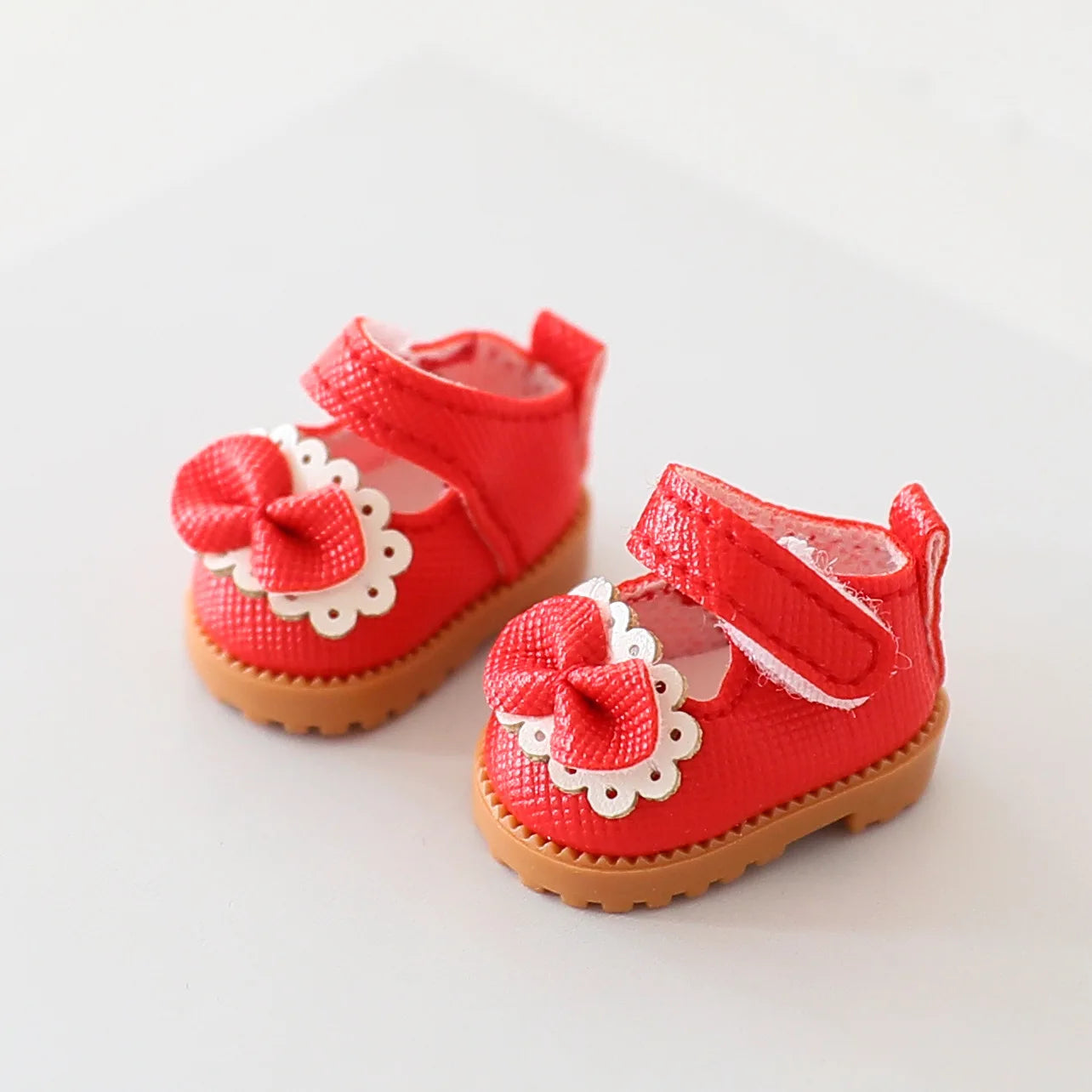 Red baby shoes with bows on a light gray background