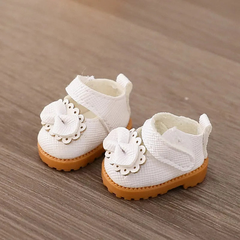 White baby shoes with flower details on a wooden surface