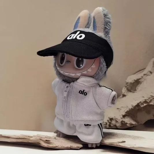 Toy figure wearing a black cap and gray outfit with 'alo' branding on a neutral background