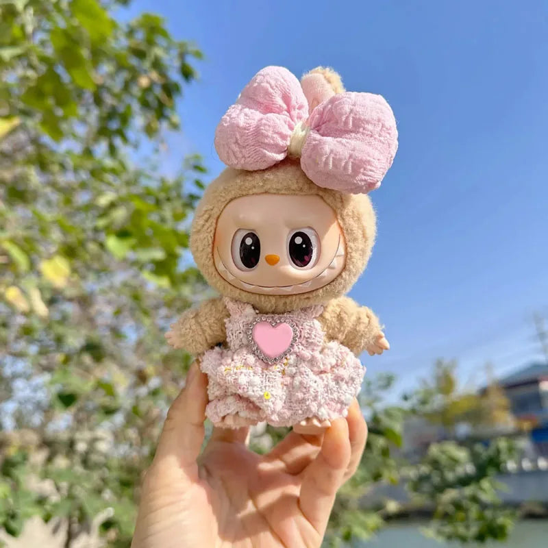Toy figure with a large pink bow held in front of a blurred natural background