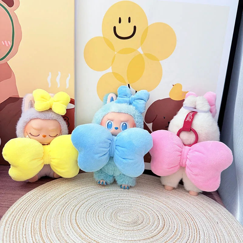 Three colorful plush toys with butterfly wings on a textured surface.