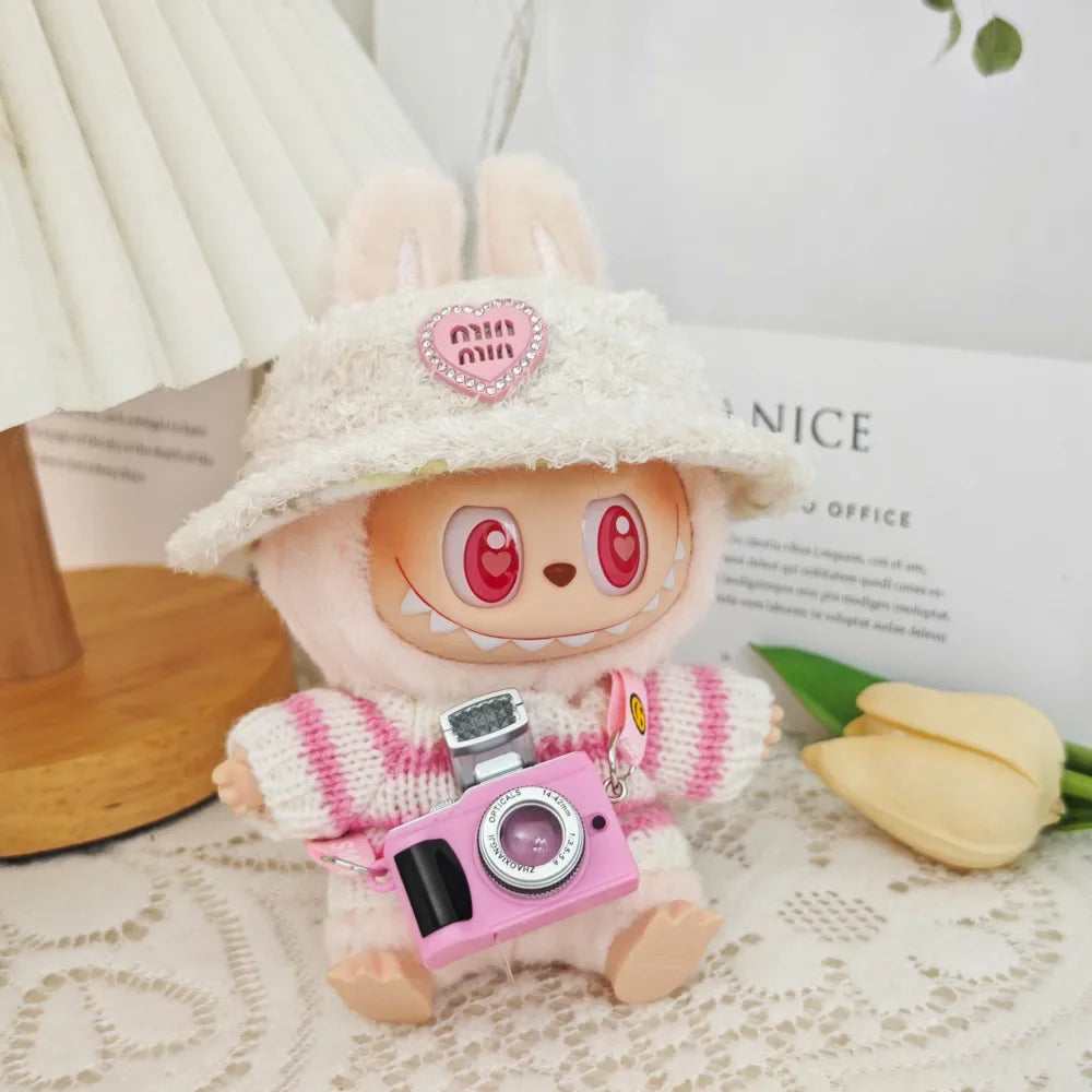 Cute plush toy with a pink camera keychain on a light surface with tulips in the background