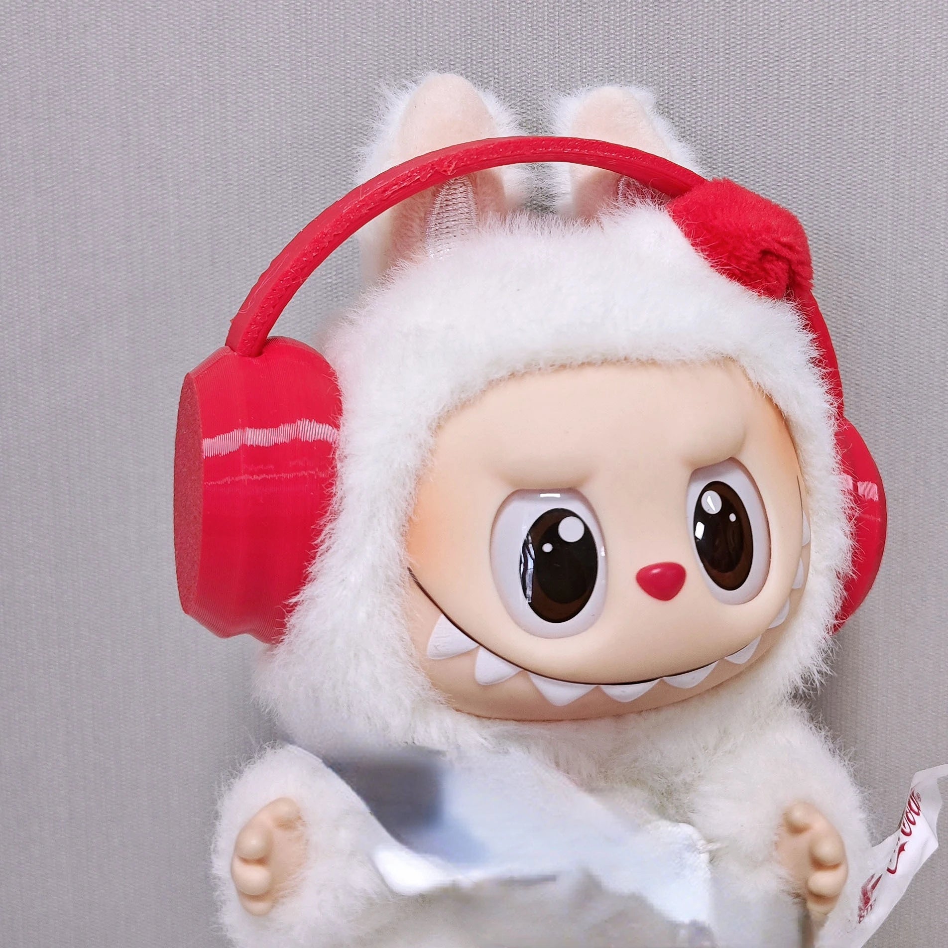 Toy figure with red headphones and a white outfit on a gray background