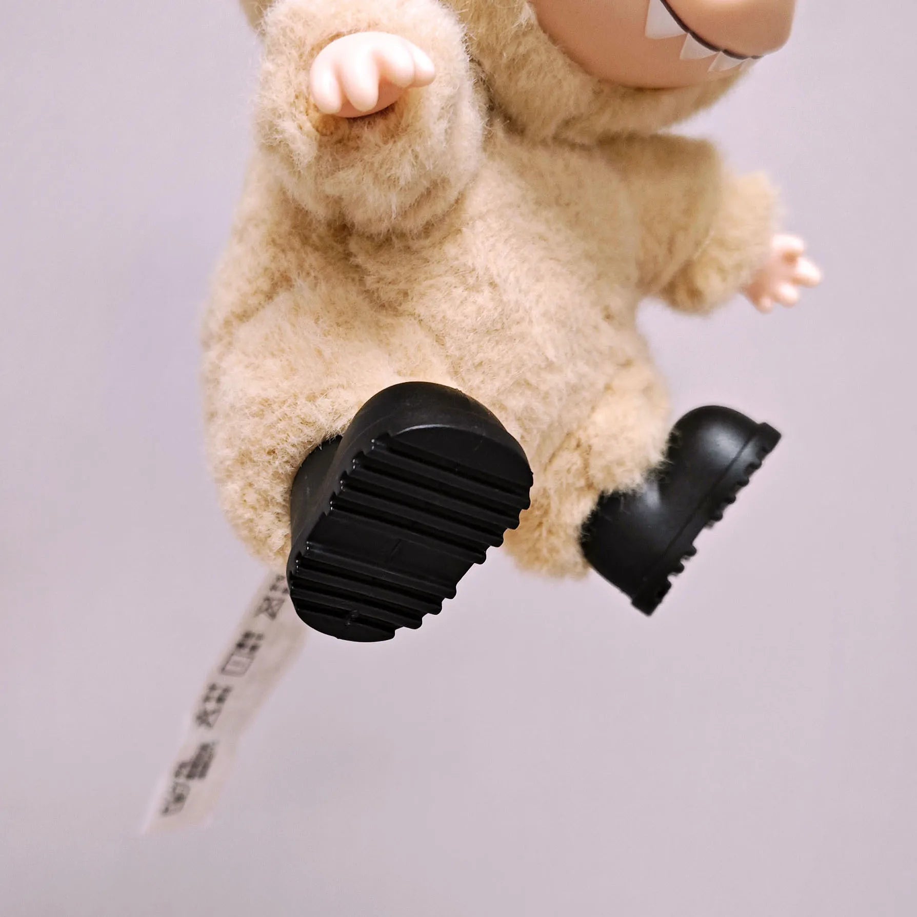 Plush toy with black shoes on a light gray background
