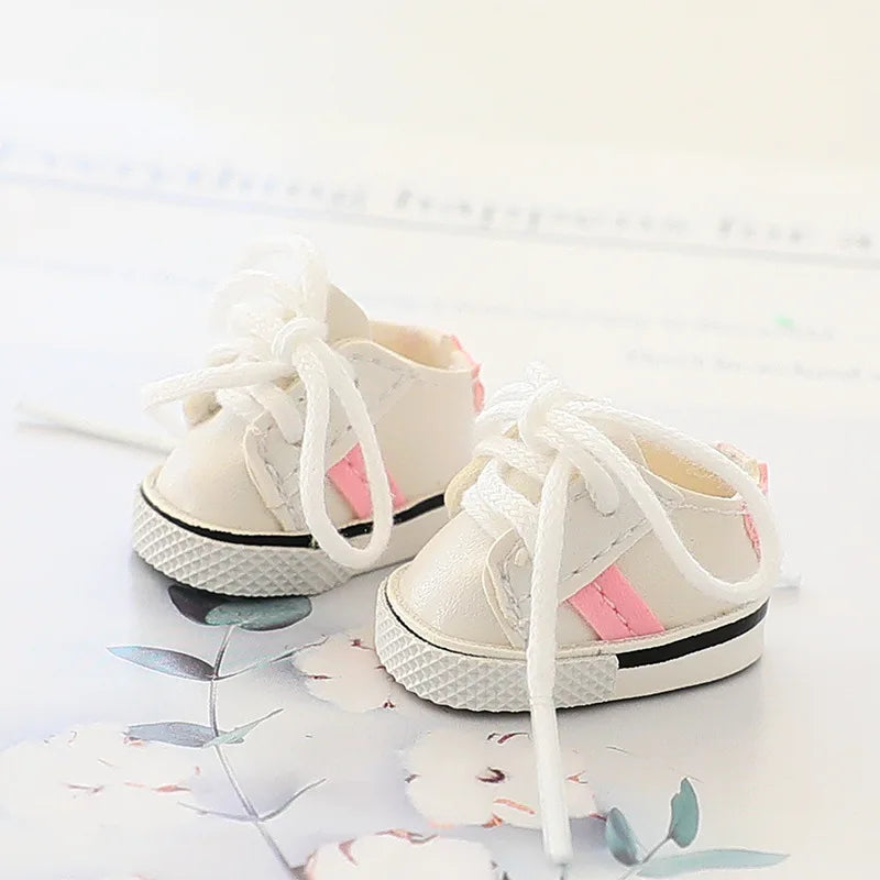 Pair of white baby shoes with pink accents on a light background