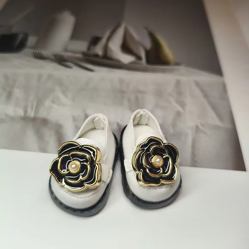 White shoes with black and gold flower designs on a white surface