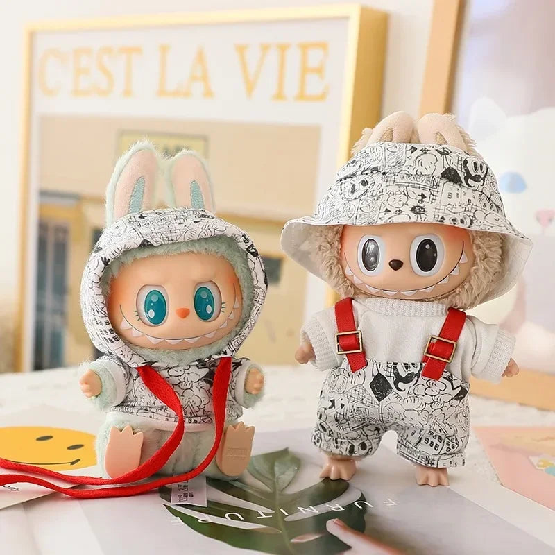 Two plush toys with bunny ears and a hat on a surface with a 'C'est La Vie' sign in the background.