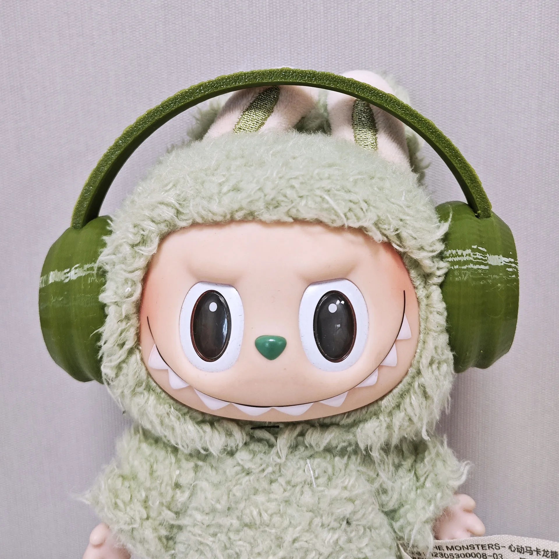 Plush toy with green headband and green outfit on a gray background