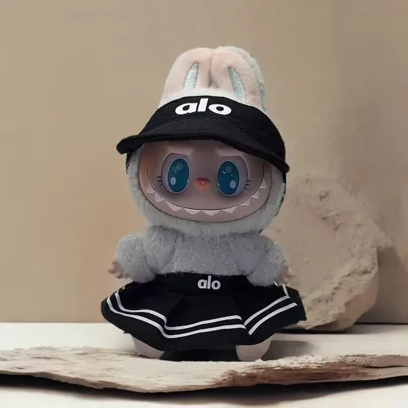 Plush toy with a black cap and skirt featuring the brand 'alo' on a neutral background.
