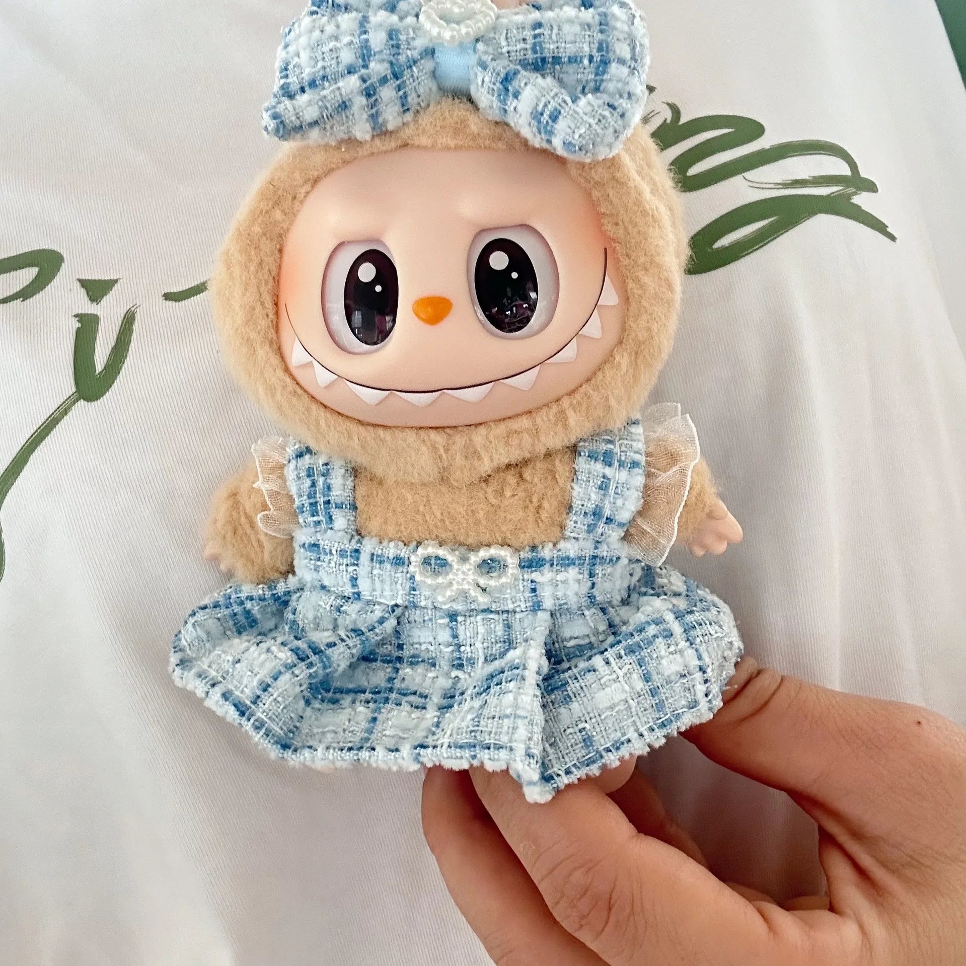Toy character with a blue checkered dress and bow held by a hand on a light background