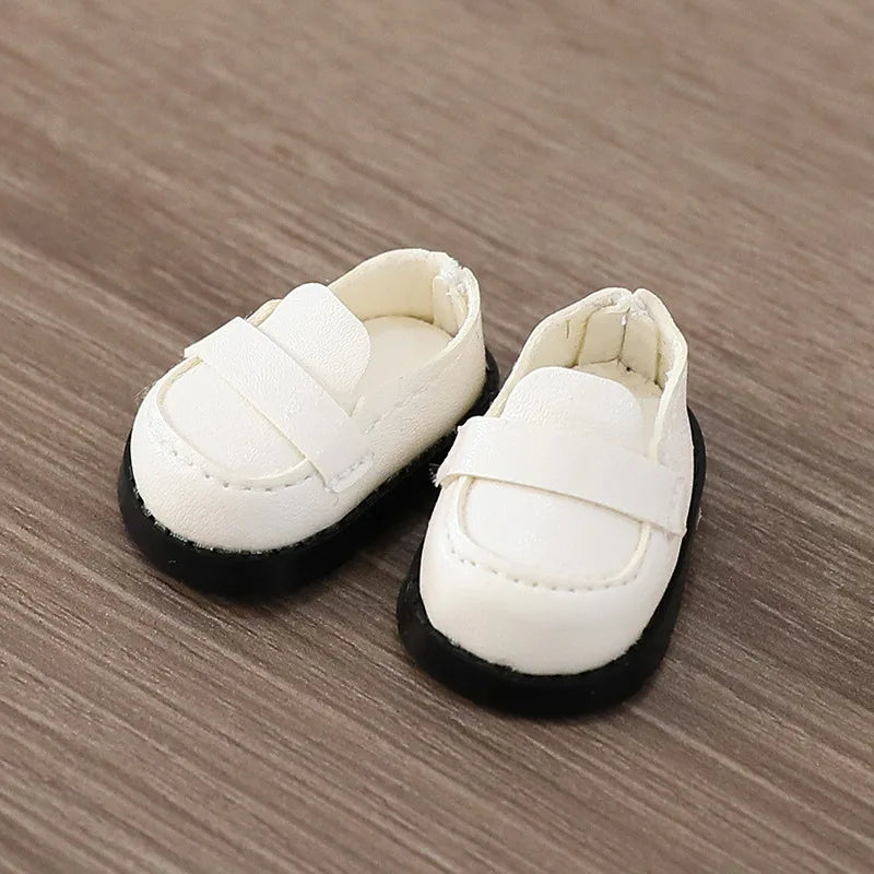 Pair of white shoes with black soles on a wooden surface