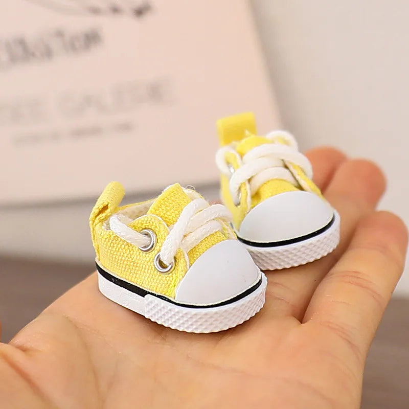 Small yellow and white sneakers held in a hand with a blurred background