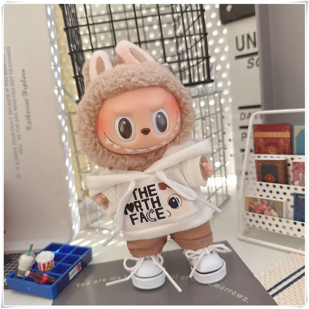 Plush toy wearing a 'The North Face' hoodie in a room setting