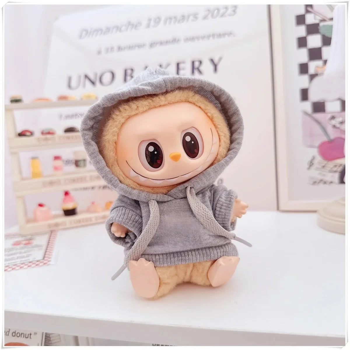 Plush toy with a gray hoodie on a surface with a magazine in the background