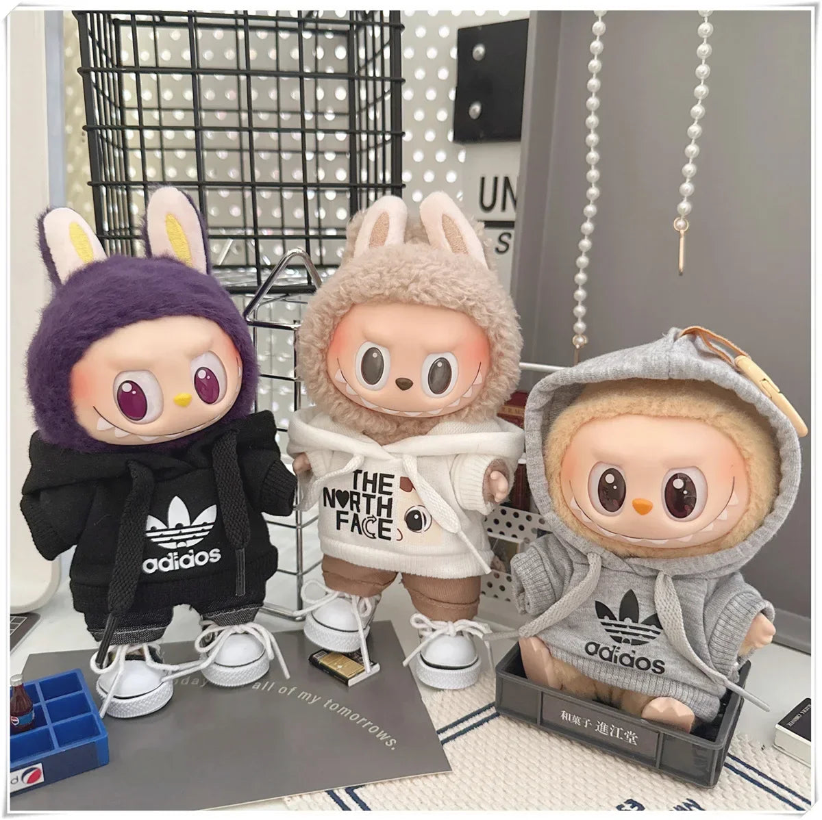 Three plush toys wearing hoodies with visible brand logos on a surface.