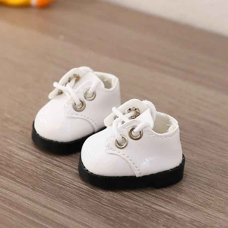 White baby shoes with black soles on a wooden surface