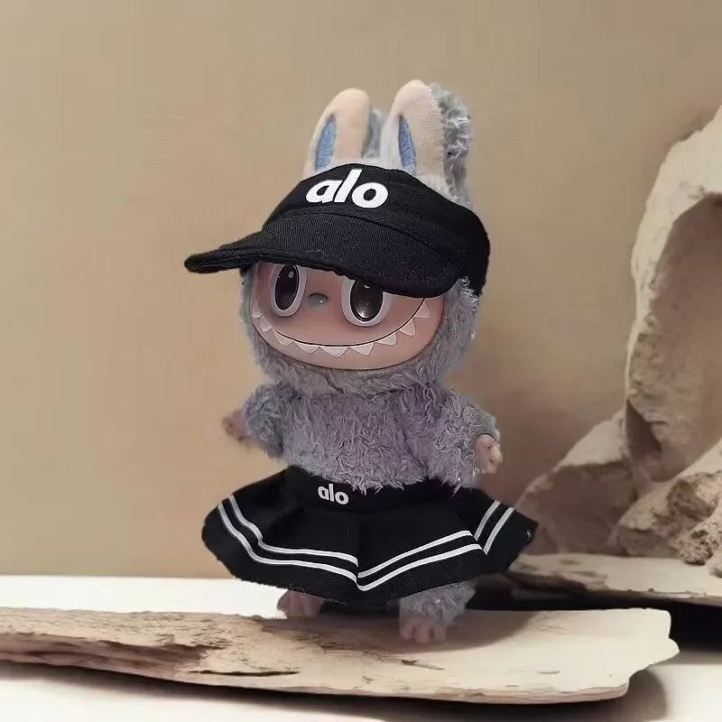 Plush toy with a black cap and skirt featuring the brand 'alo' on a neutral background.