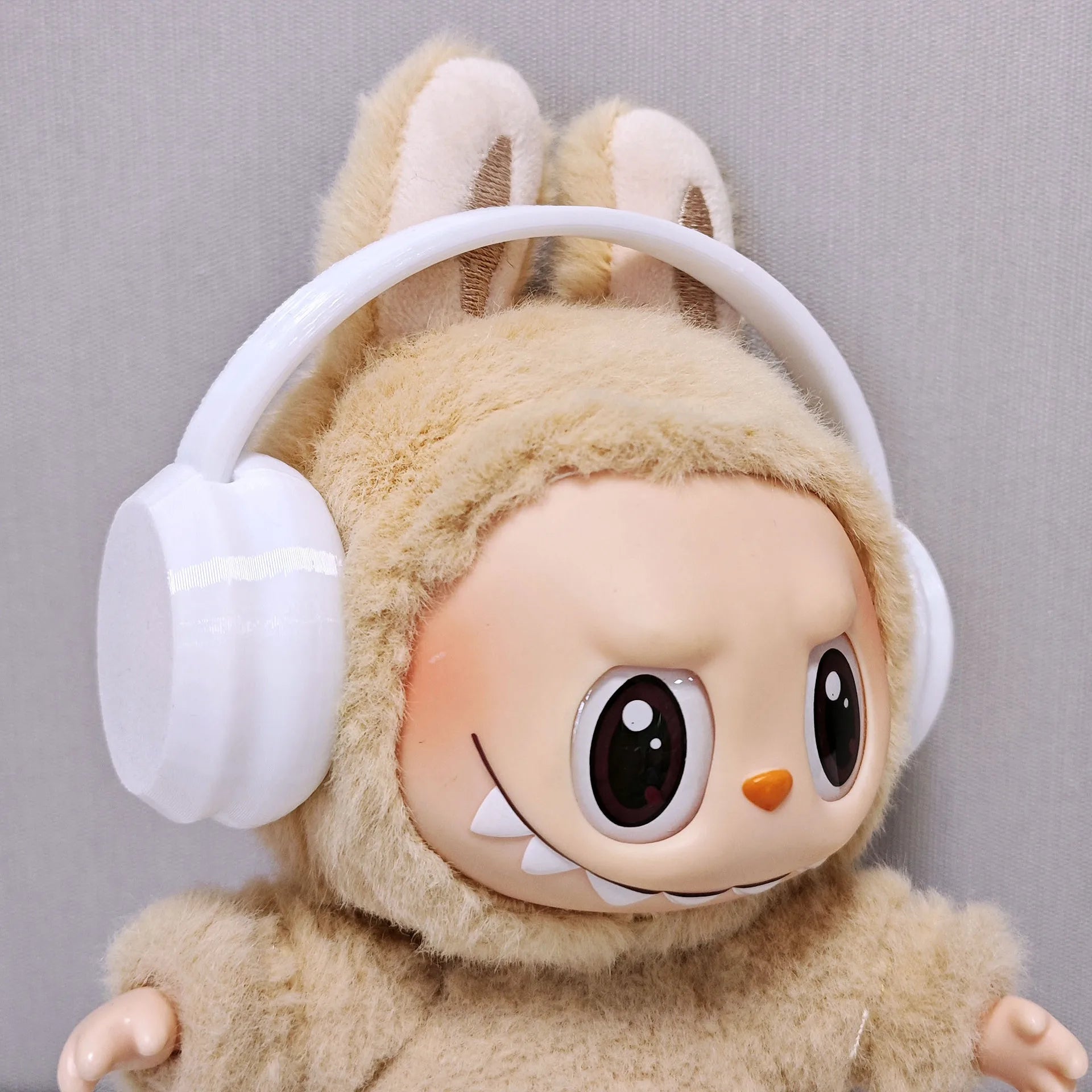 Plush toy with bunny ears and white headphones on a gray background