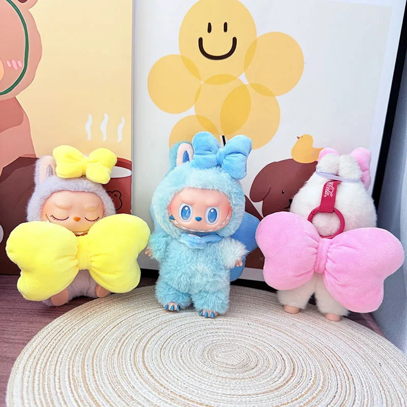 Three colorful plush toys with butterfly wings on a textured surface.