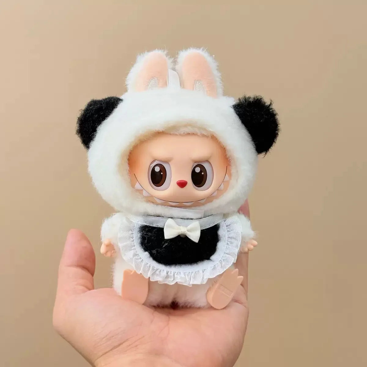 Toy figure of a character in a panda costume held in a hand against a beige background